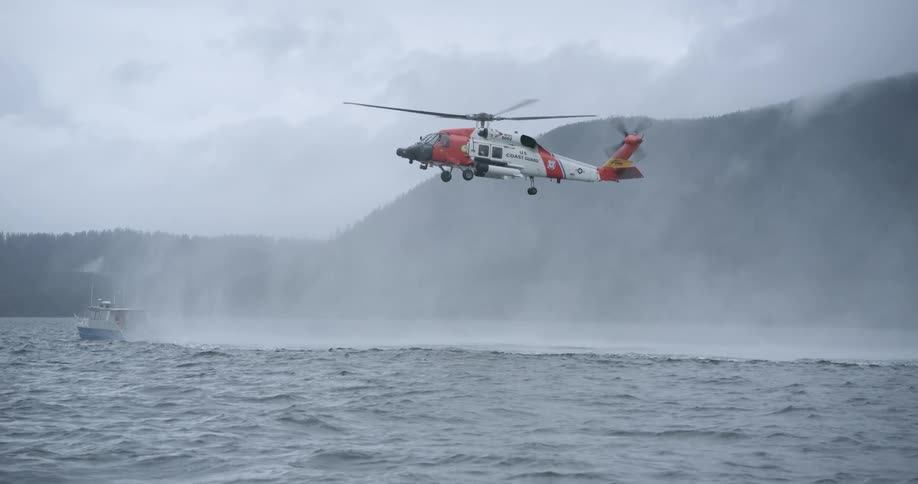 The rescue helicopter is flying above the boat in the ocean
