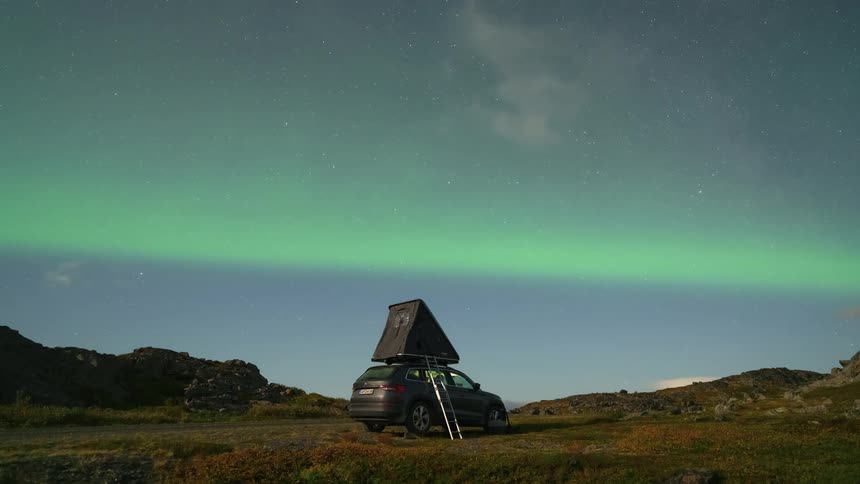 A tent is on top of the car camping in the wilderness