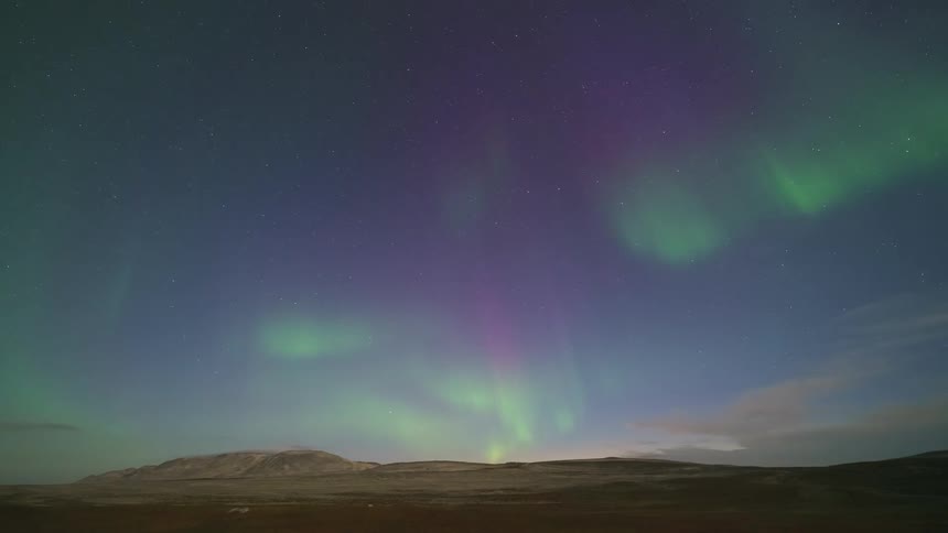 The northern lights move slowly over the field