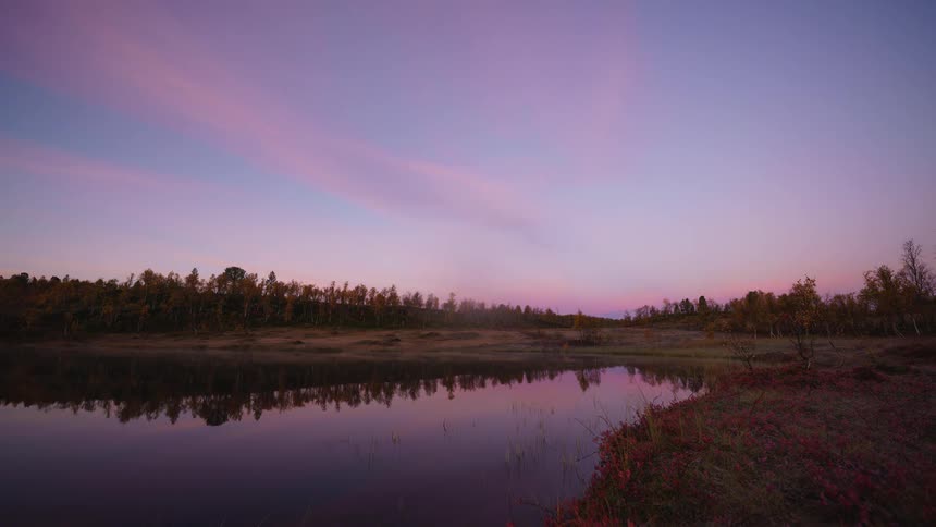 The sun rises as the northern lights shine