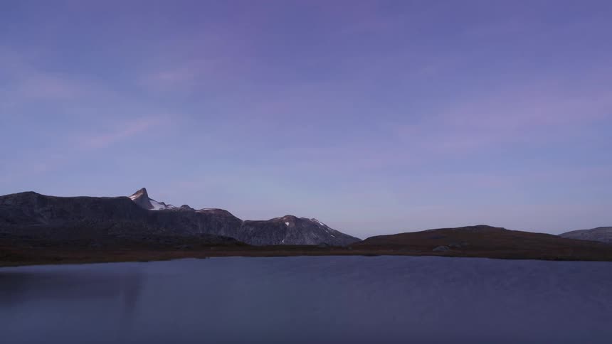 Mountains along the coast as the glowing lights of the aurora borealis move across the sky