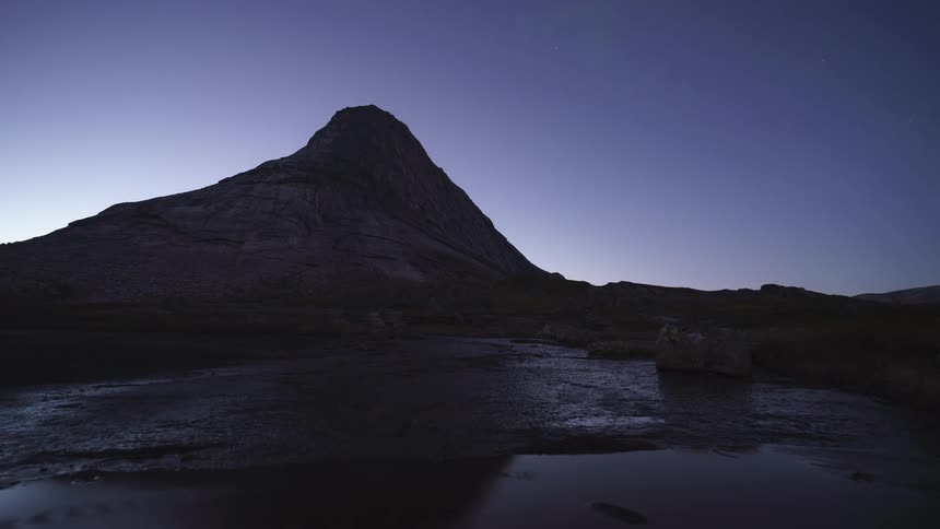 Aurora borealis and other movements on the sky next to a natural landscape with a pond and a mound outdoors