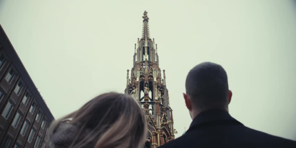 Couple looks at an ornate historic tower from an urban square