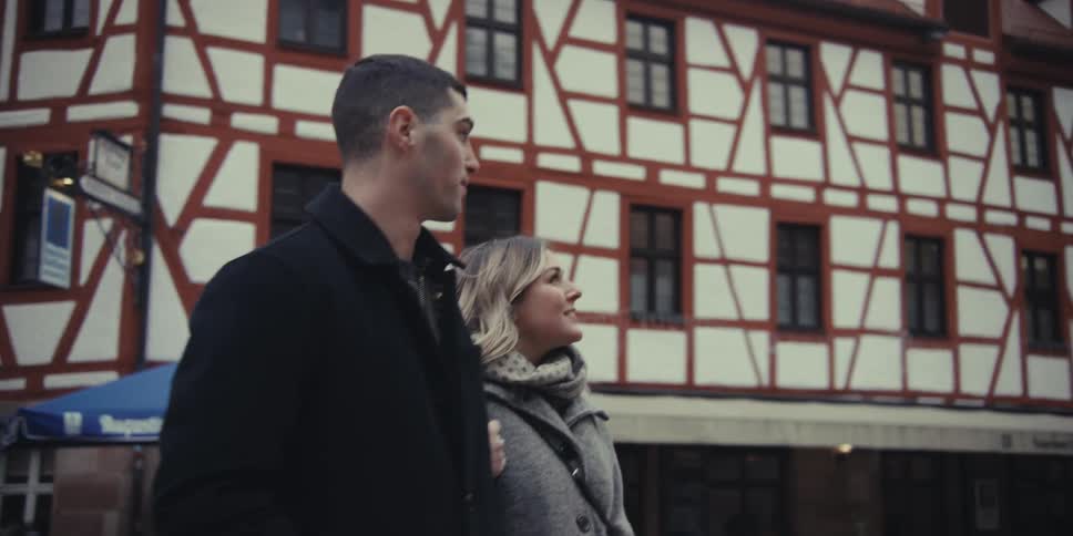 Couple walks side by side in front of a halftimbered historic building