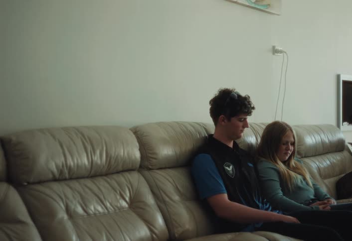 Young couple sits on a large couch holding hands