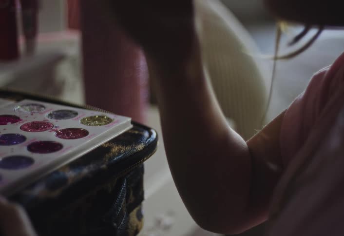 A child putting on makeup in a room