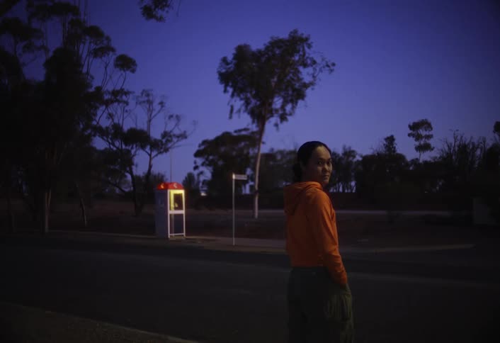 Young woman standing by the road in the evening turns to look over her shoulder