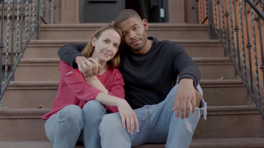 Man and woman sitting outside on front steps embracing and smiling