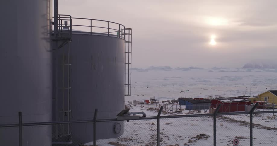 Multiple storage tanks tower over a town on an overcast winter day