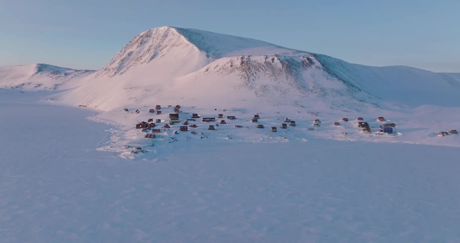 Aerial of an isolated coastal village near an arctic mountain range