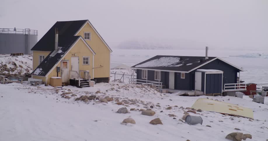 Houses surrounded by snow on an arctic region close to the ocean outdoors during day time