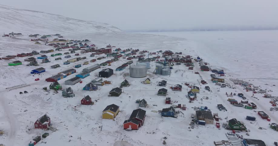 Houses on a snow covered mountain hill overlooking the frozen coast