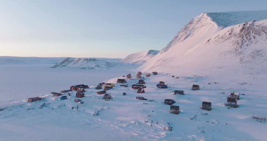 Houses at the foot of a snow covered arctic mountain