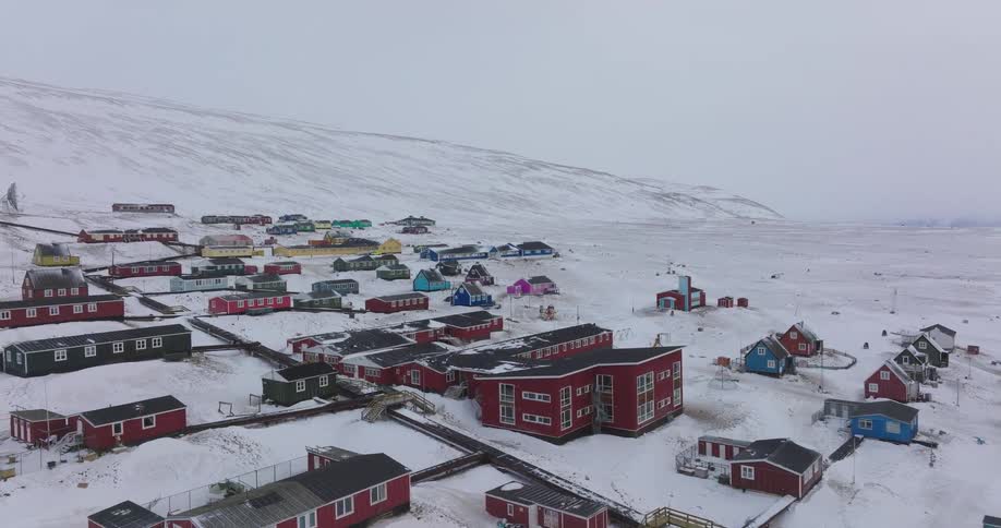 Polar settlement covered in snow with colorful houses spread across a hillside and plain
