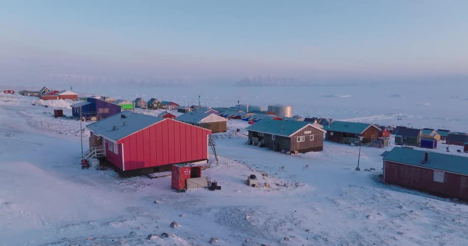 Snowcovered polar settlement with colorful houses near a frozen coastline