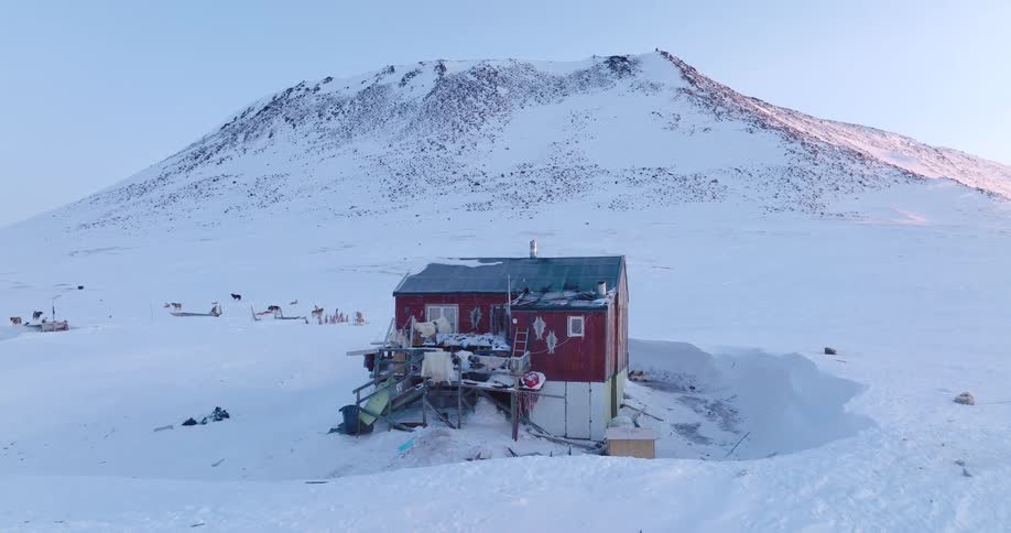 The shack is by the bottom of the mountain in the snow