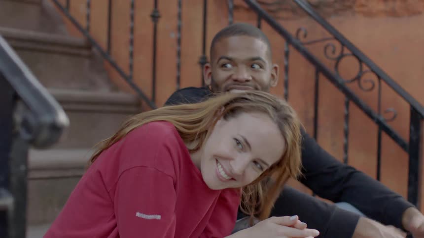 A man and woman laugh together on the steps