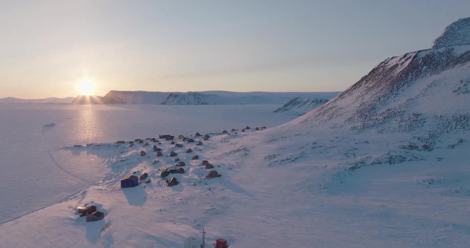 Coastal town stands near a snowy mountain on a sunny winter day