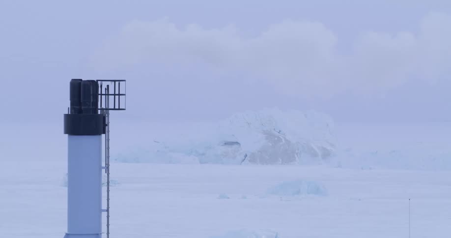 Smoke from a tower overlooking the frozen arctic moves across the sky