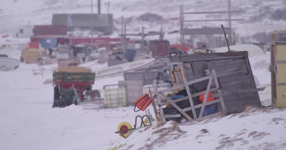 Tilted wooden structure with scattered equipment in a snowcovered settlement