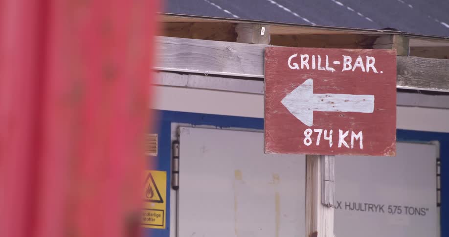 Road sign in front of a building pointing to the direction of a grill bar