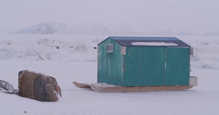 Mobile shelter on a sled in a snowcovered polar area with ice formations in the background