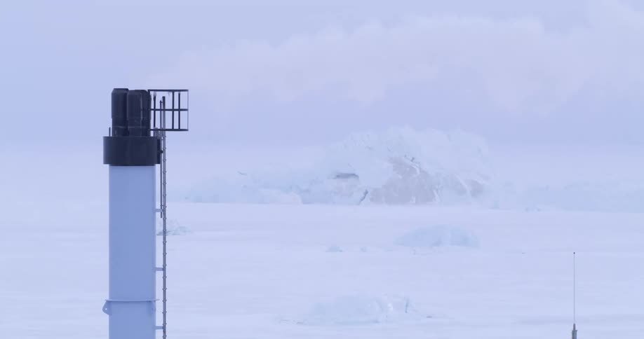 Smoke from a tower overlooking the frozen arctic moves across the sky