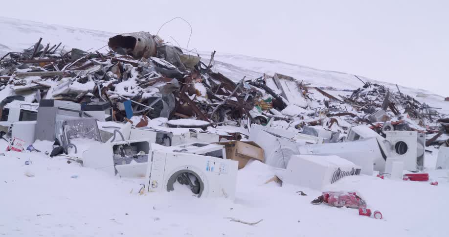 Bird flying over snow covered debris and junk at the dump