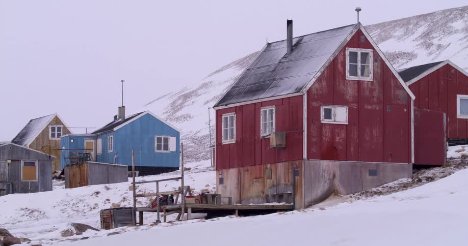 Wooden house in a snowcovered polar settlement with other buildings in the background