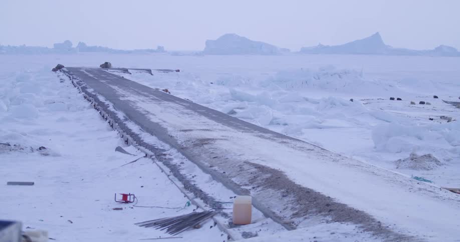 Frozen dock over arctic ice on the coast as birds fly onto the snow