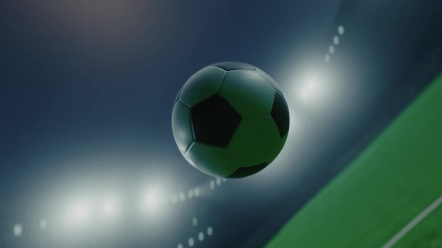 Soccer ball floats above the soccer field during a stadium game at night