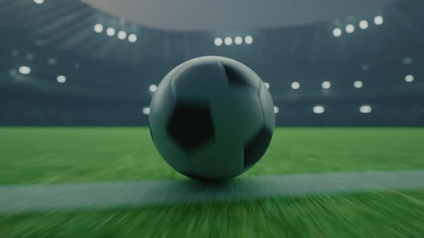 Soccer ball rolling over the grass under stadium lighting