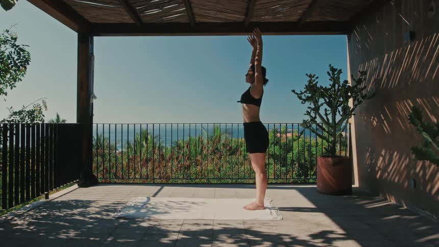 Person practicing yoga stretching on a terrace overlooking the sea