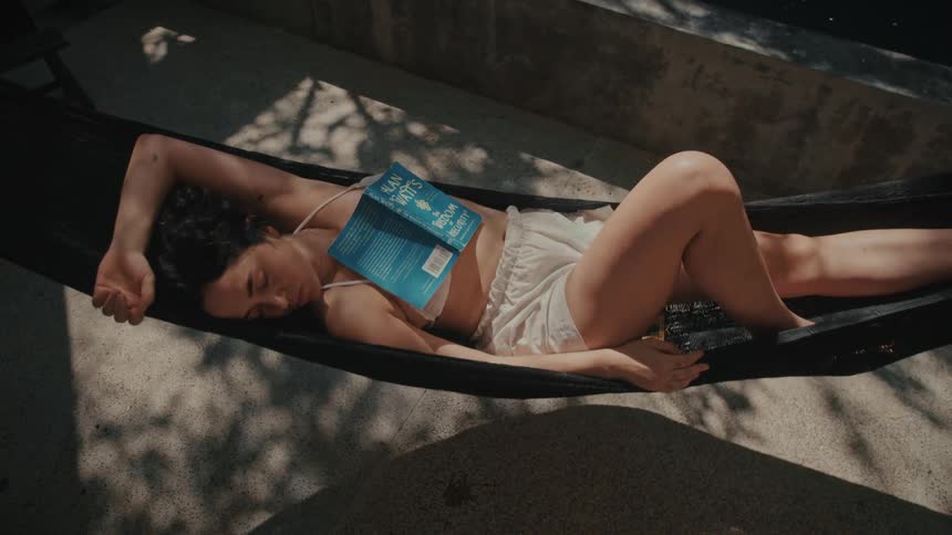 A woman laying outdoors in a hammock