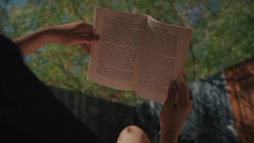 A woman reading a book while laying outdoors