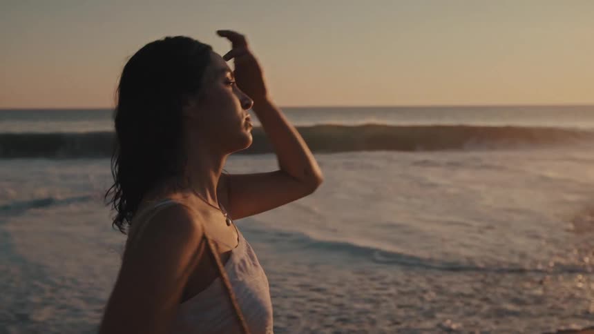 The woman walks on the beach at sunrise