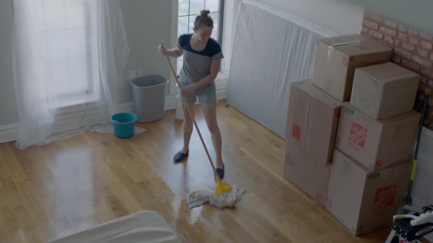 A woman mops a wood floor