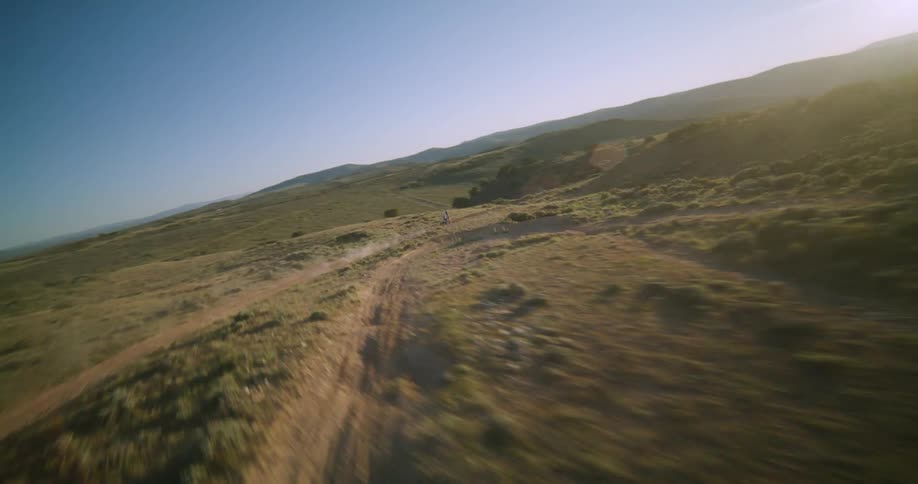 Motorcyclist rides a dirt bike along a rural dirt track on a sunny day