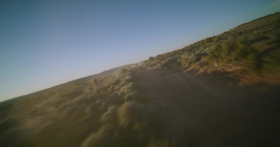 Biker riding a motorcycle on a dust road surrounded by trees and vegetation outdoors during day time
