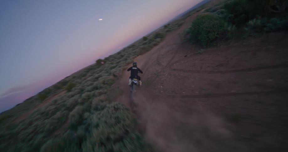 Motocross rider riding a bike on a dirt trail at dusk