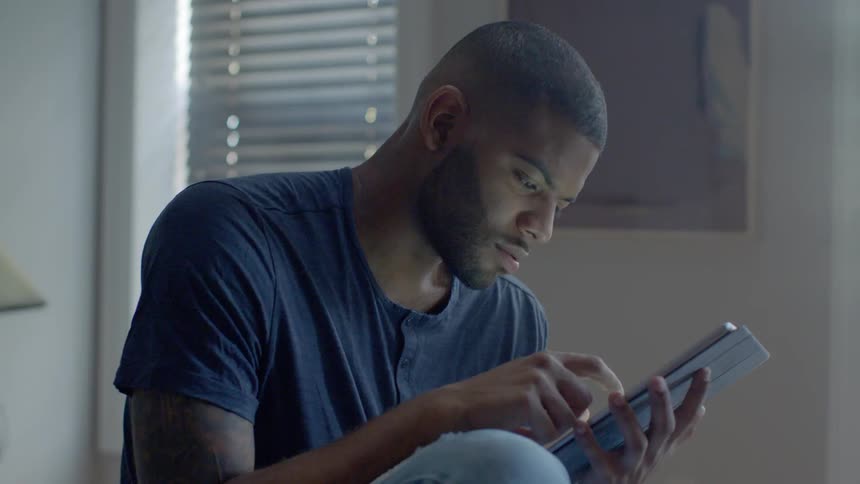 A man uses a tablet in the bedroom