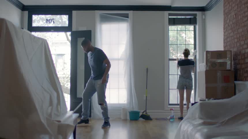 Man and woman dusting and cleaning floors in apartment home