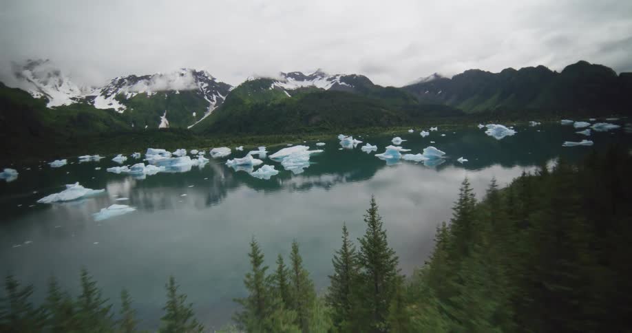 Lake with floating ice blocks surrounded by forest and snowcovered mountains