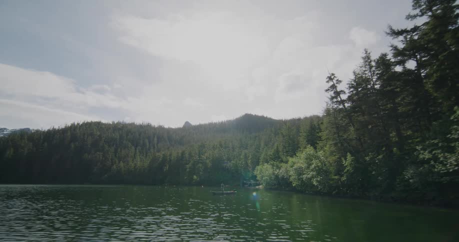 Fisherman in a small boat off the coast of forested mountains