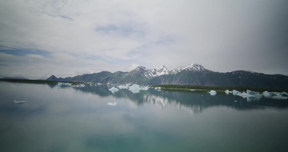 Pieces of ice floating on a lake near the shoreline on a region with a mountain range outdoors during day time
