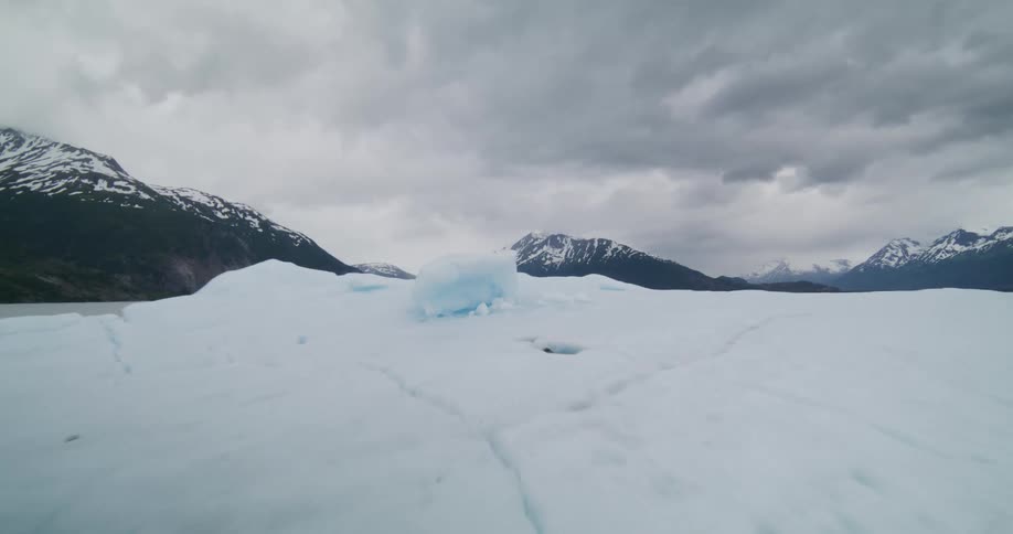 Mountains along the coast with a large piece of ice floating on the water