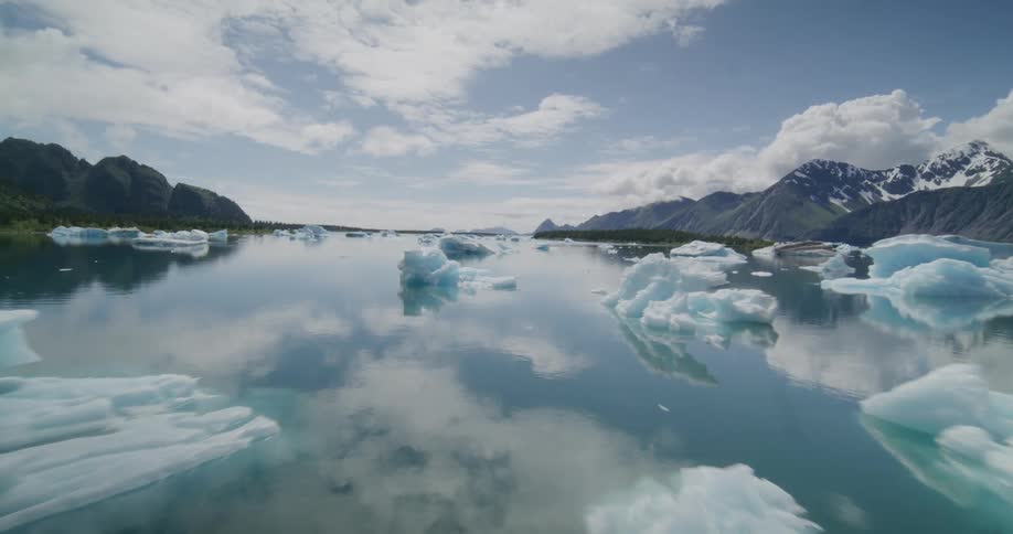 Forests and mountains along the coast as large pieces of ice float on the water