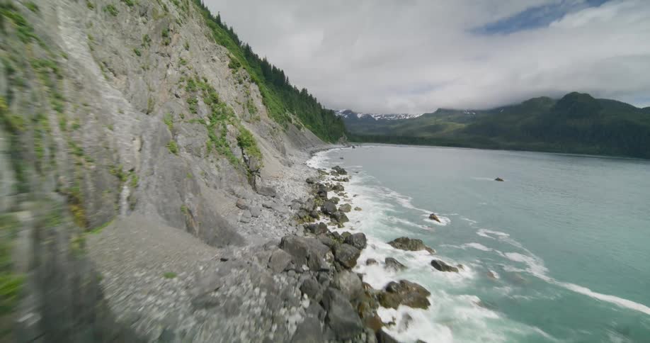 Mountain with a steep cliff along the coast as waves splash into rocks below