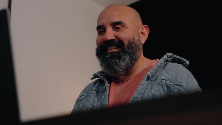 Man smiles and nods his head as he sits in front of a computer