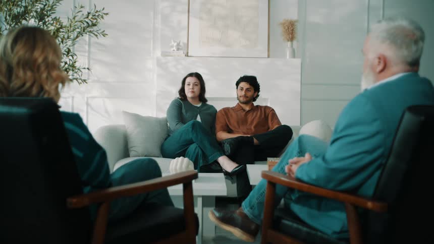 Group of people seated in a living room engaged in a conversation indoors